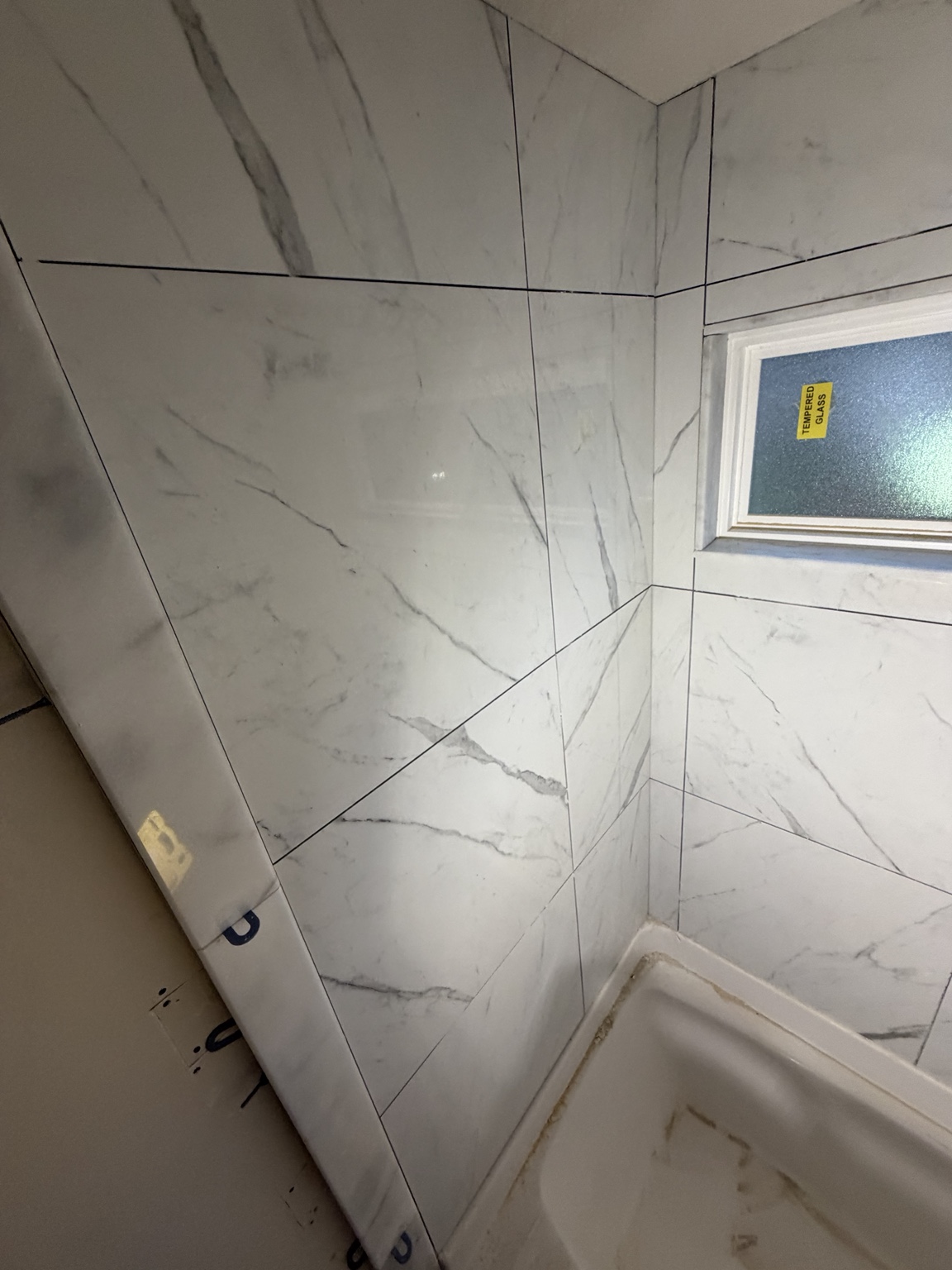 Close detail of marble-look wall tile and a tempered-glass shower window